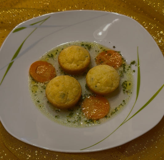 Drei lockere Kräuter-Schöberl mit Karottenscheiben und Schnittlauch in klarer Suppe