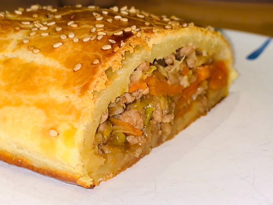 Angeschnittener Krautstrudel mit Sesam und sichtbarer Kraut-Fleisch-Füllung mit Karotten
